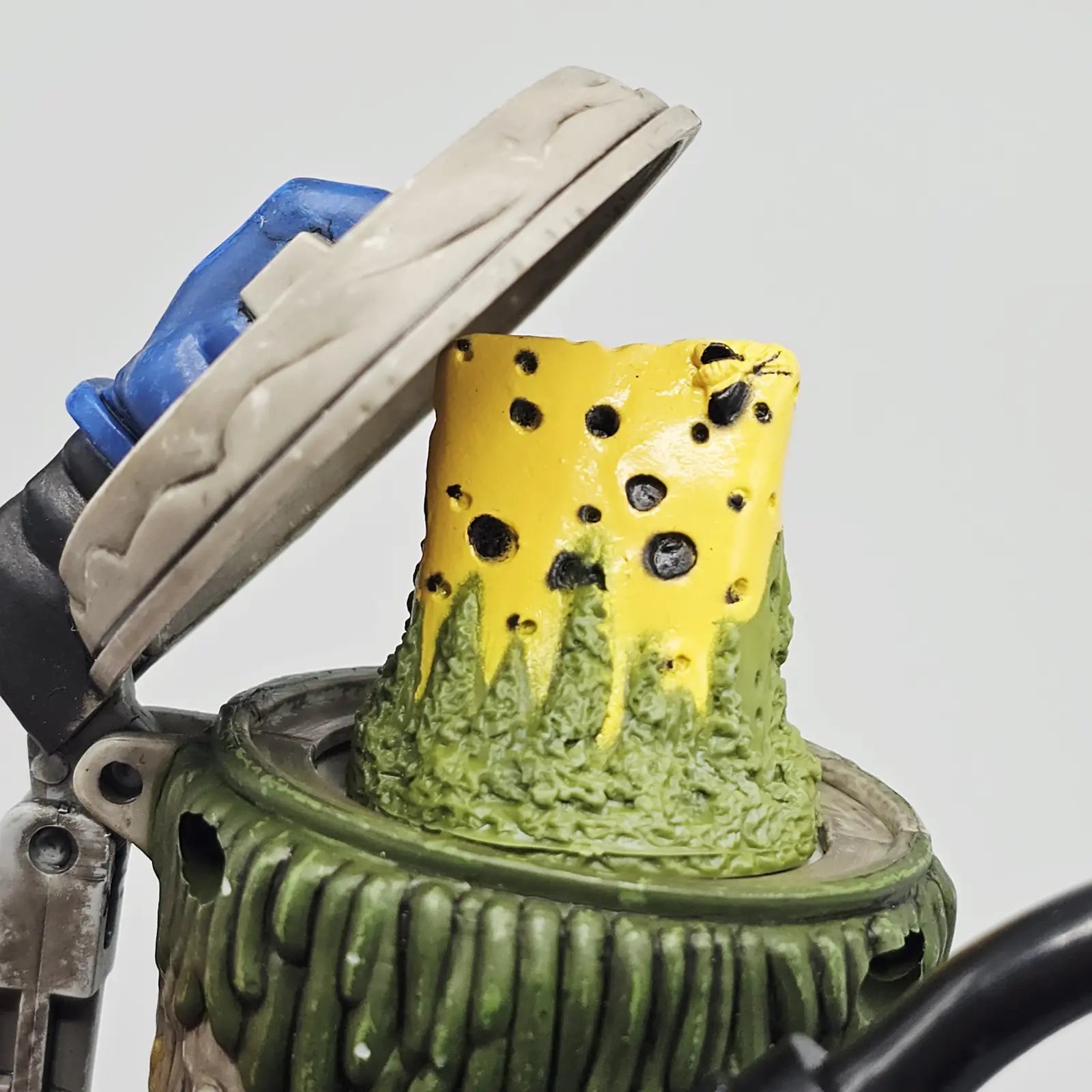 Toy figure of a creature with a yellow and green design on a gray background