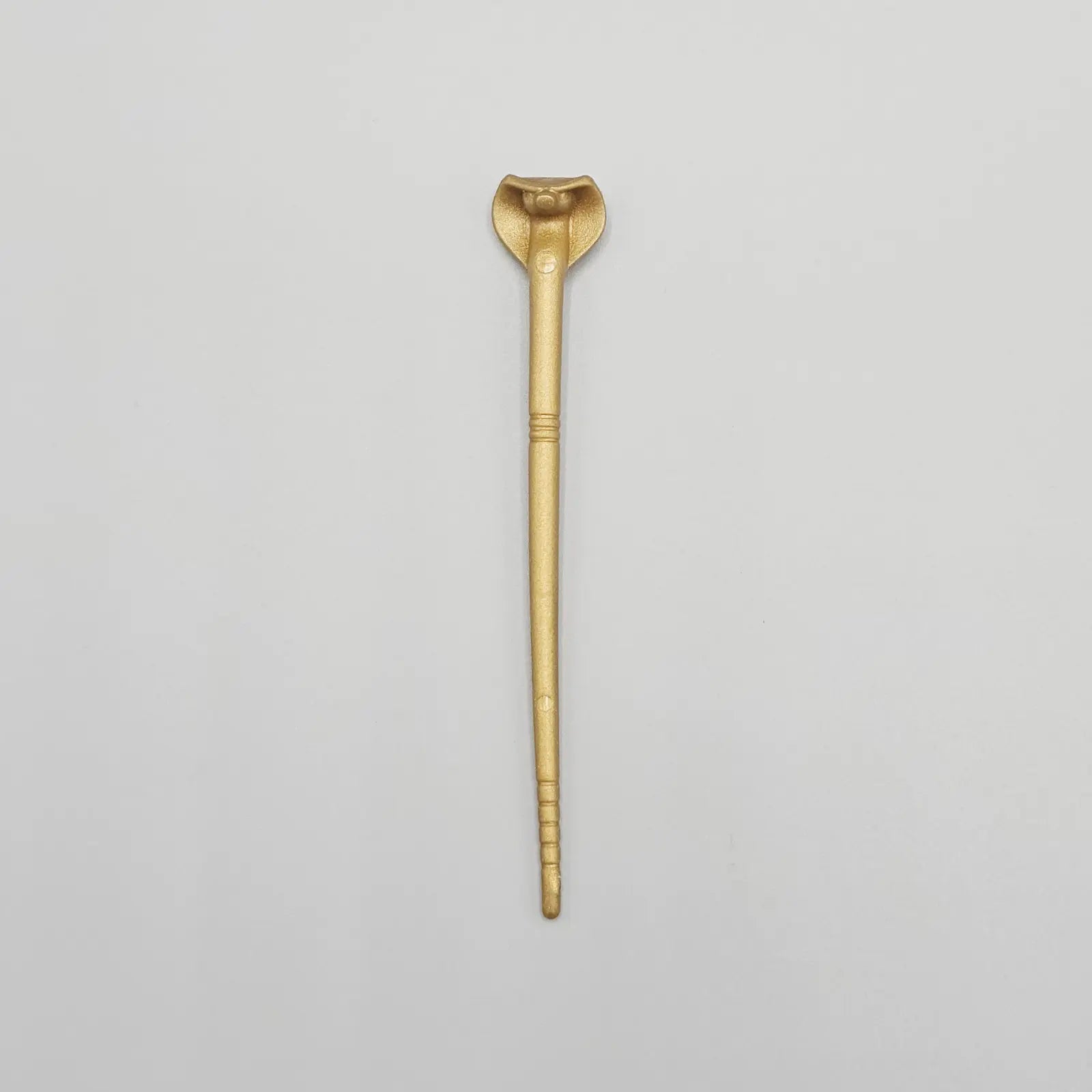 Gold action figure snake staff on grey background