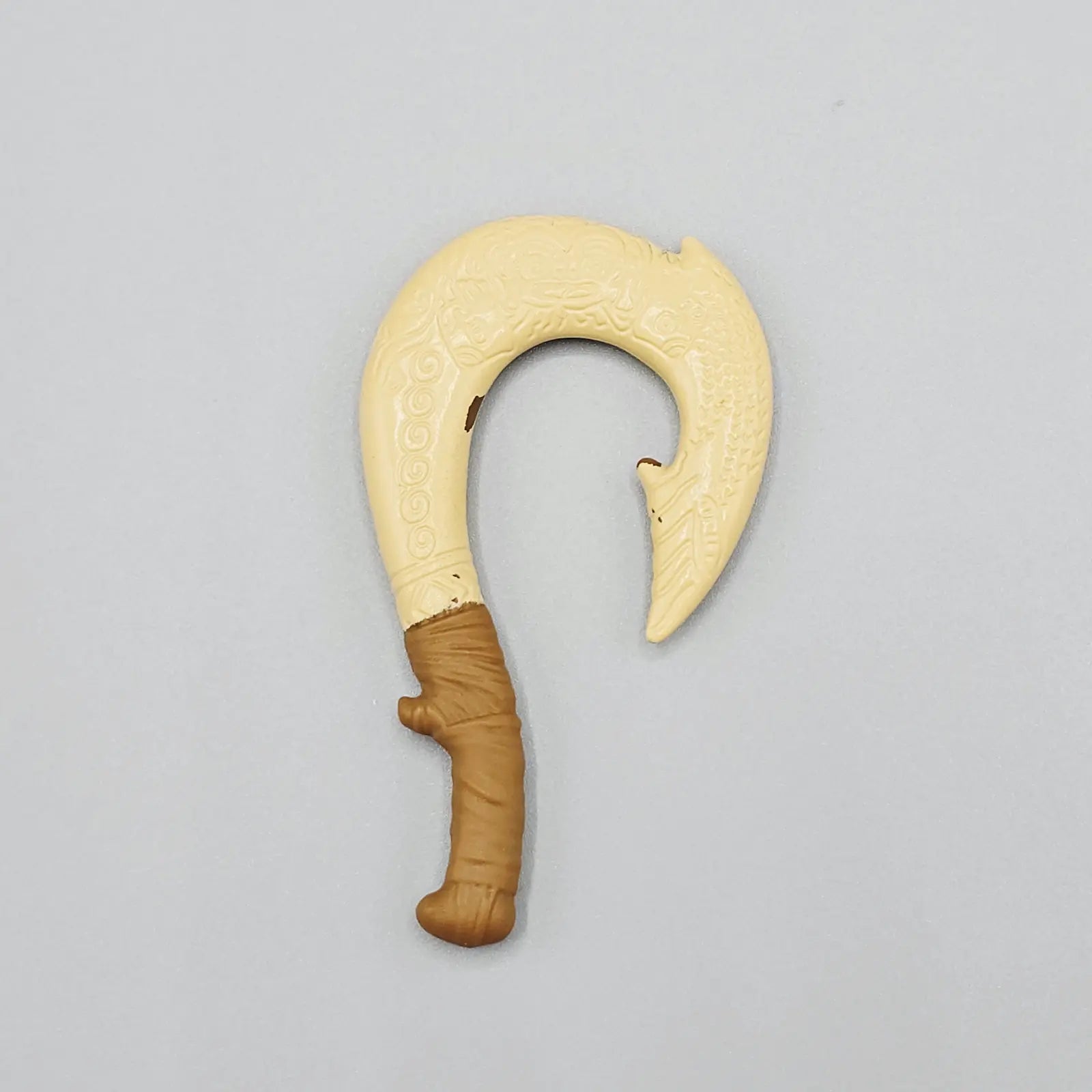 Decorative weapon with a curved blade and brown handle on a gray background