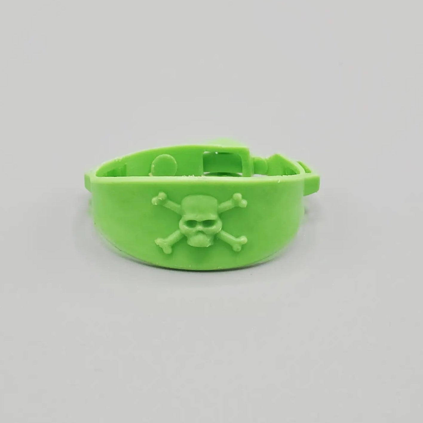 Green action figure belt with skull and crossbones on a gray background
