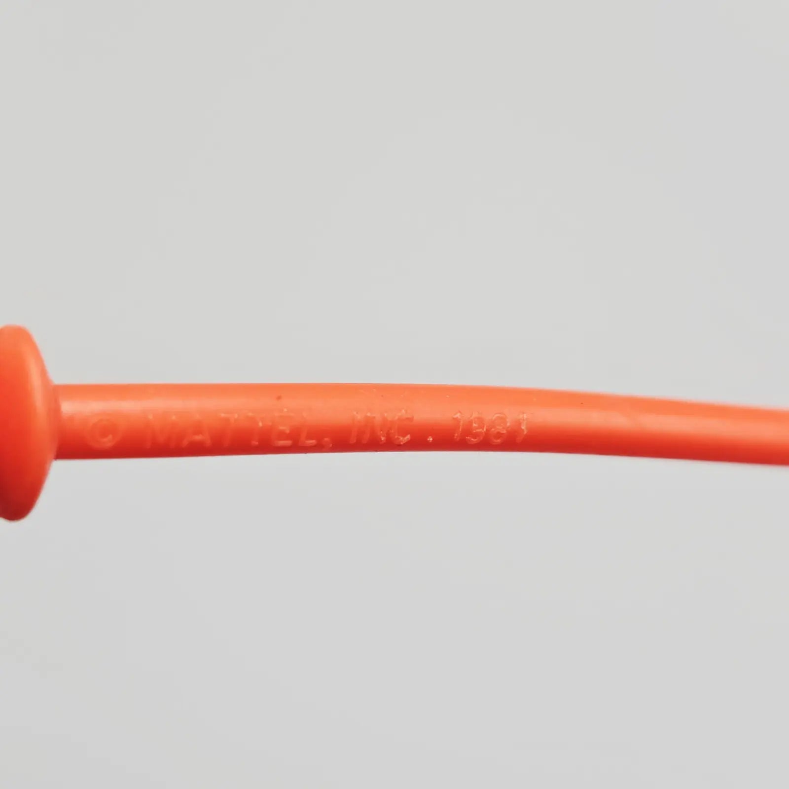 Close-up of an orange plastic tube on a gray background