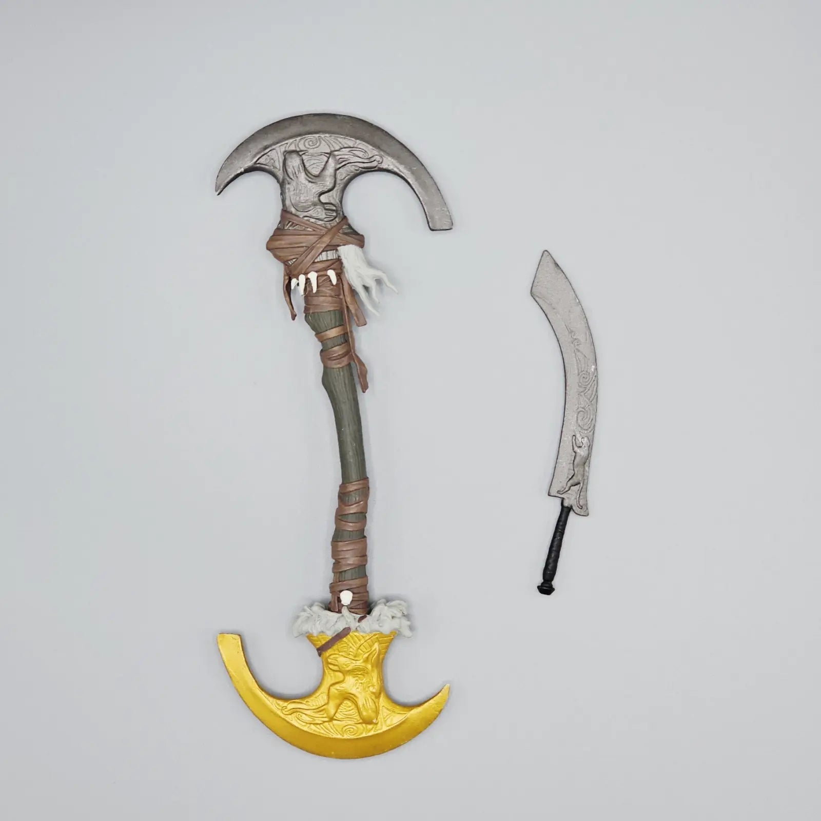 Decorative weapon with a large axe head, sheath, and small blade on a light gray background