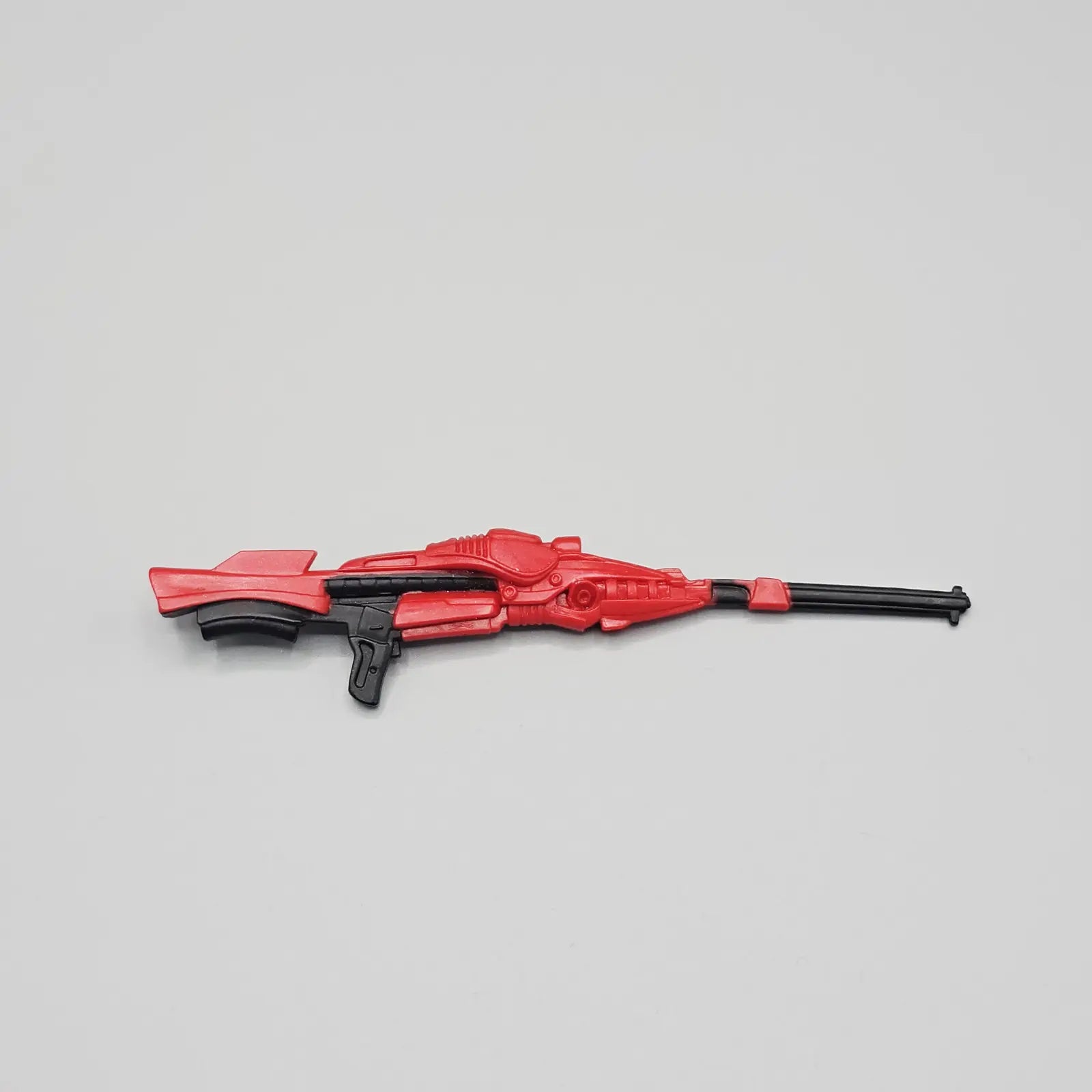 Red and black toy gun on a gray background