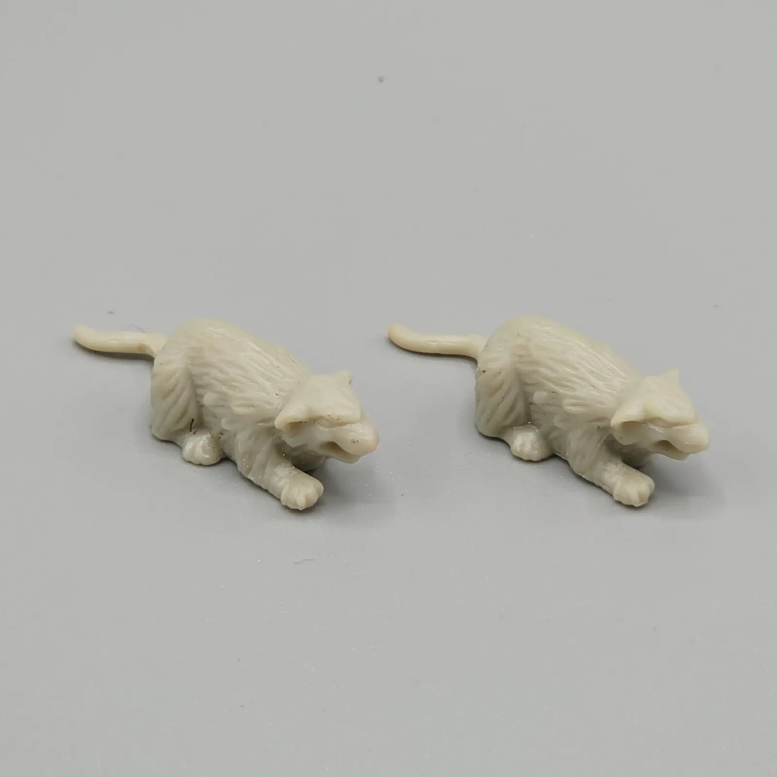 Two small white rat figures on grey background