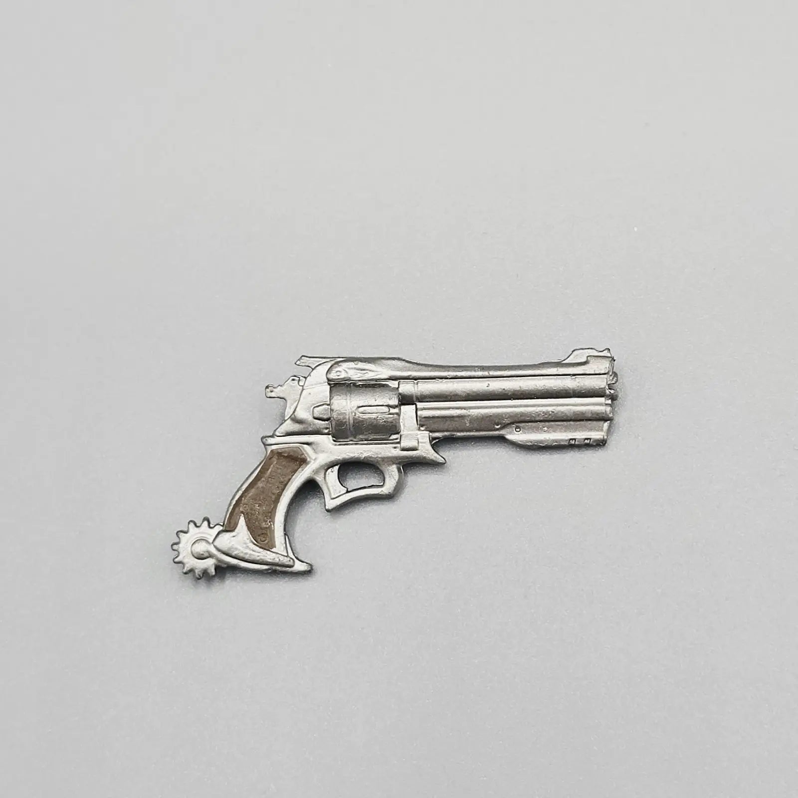 Silver revolver charm on a gray background