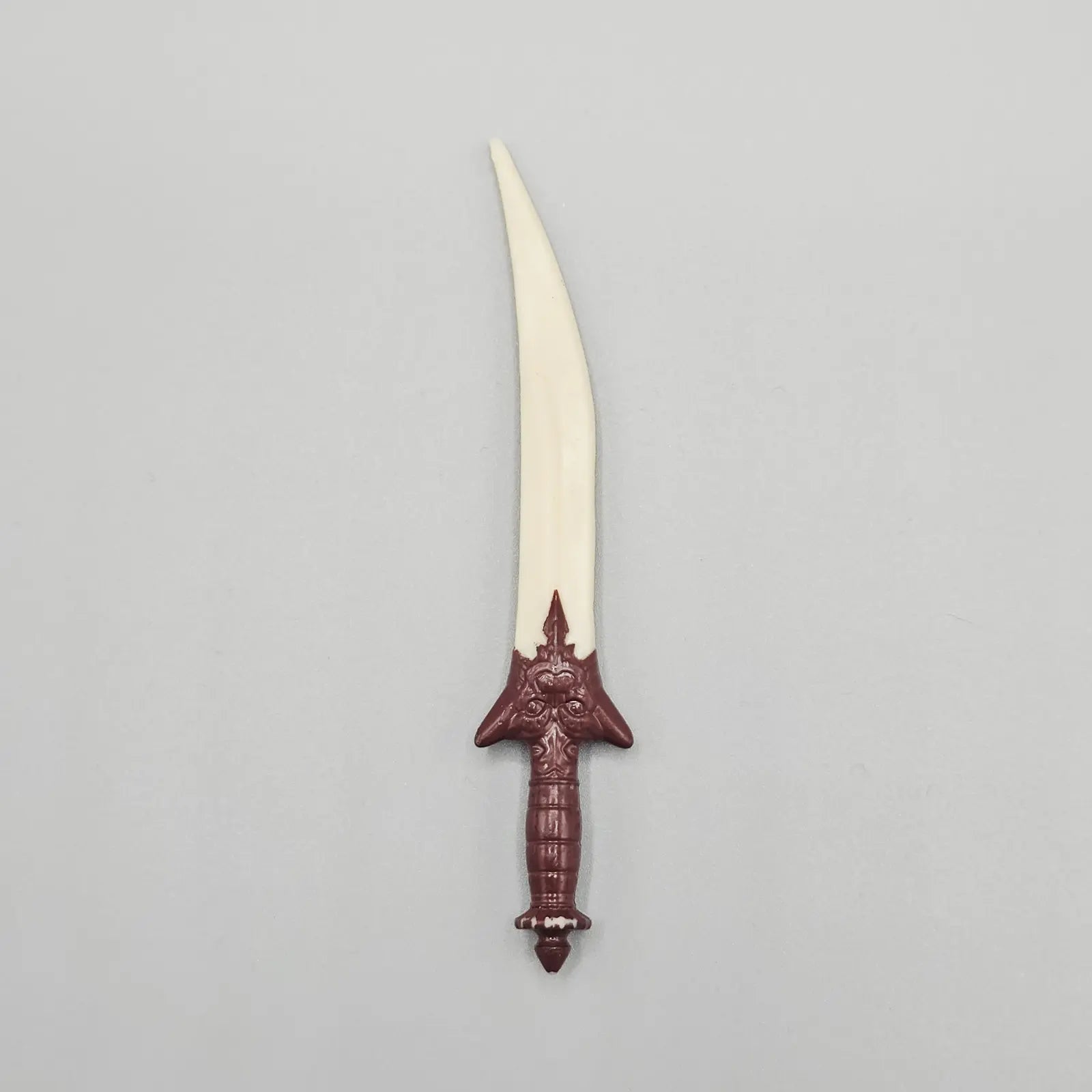 Decorative dagger with a white blade and red hilt on a gray background