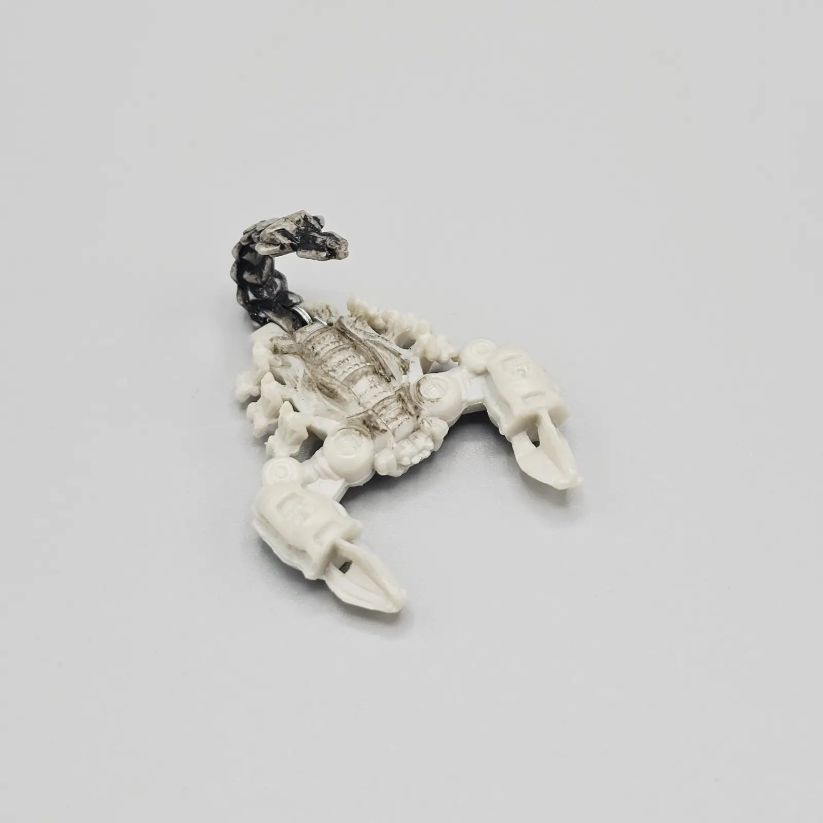 Scorpion-shaped object on a light gray background